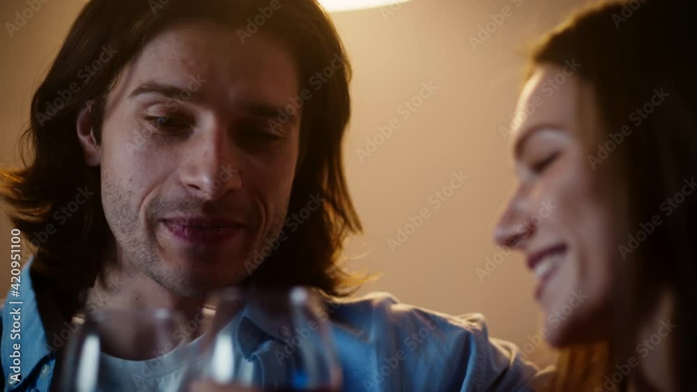 Young couple in love drinking wine and laughing, talking to each other in evening at home, slow motion, close up Young couple in love drinking wine and laughing, talking to each other in evening at home, slow motion, close up
