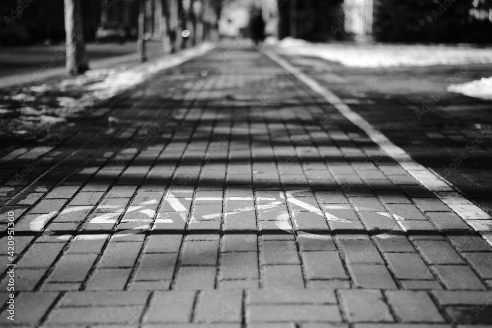 Life in the city. Bicycle sign on the sidewalk marking a bike path. Black and white image.