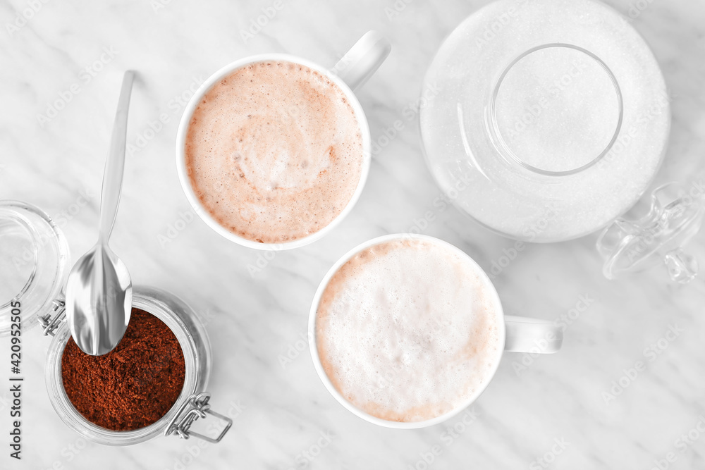Composition with cups of tasty latte and coffee powder on light background Composition with cups of tasty latte and coffee powder on light background