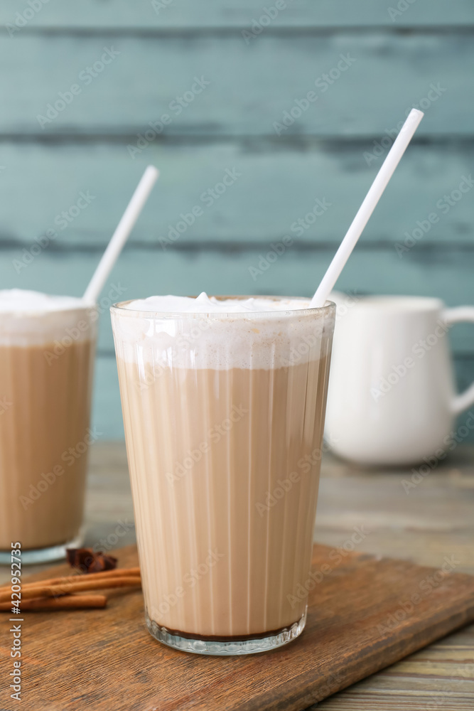 Glasses of tasty latte on color wooden background