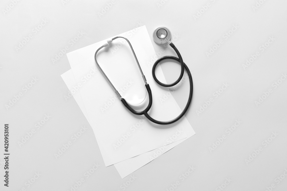 Modern stethoscope and sheets of paper on light background Modern stethoscope and sheets of paper on light background