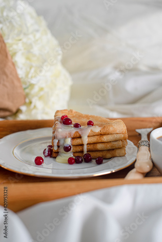 Food tray. Thin pancakes with condensed milk and berries. Romantic breakfast with pancakes and coffee and flowers in bed. Copy space