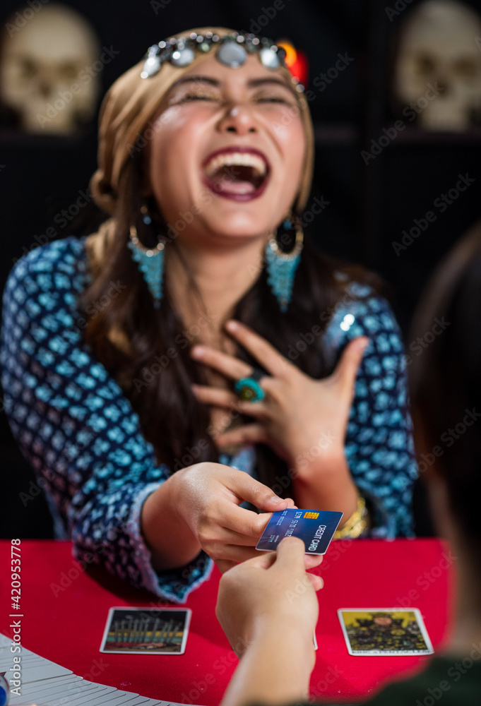 Fototapeta premium Happy fortune teller taking credit card from client