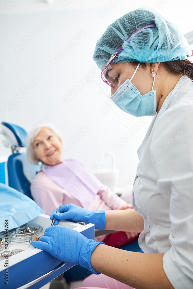 Qualified dental practitioner looking for necessary tool on table Qualified dental practitioner looking for necessary tool on table