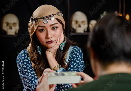 Billede på lærred Confident Asian sorceress taking money from customer
