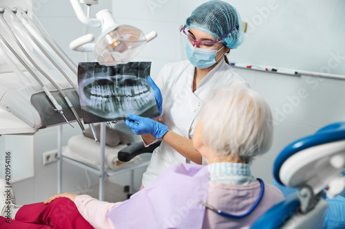 Canvas Print Dentist introducing dental x-ray to a female in medical chair