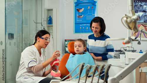 Billede på lærred Stomatologist explaining proper dental hygiene using presentation teeth skeleton, extracting a mass from it