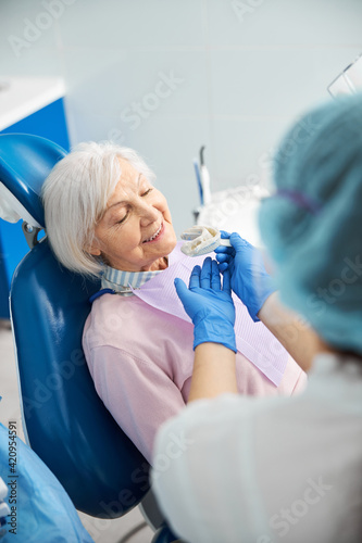 Optimistic senior person getting offered teeth impression
