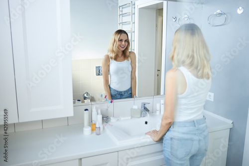 Charming woman looking in the mirror in bathroom
