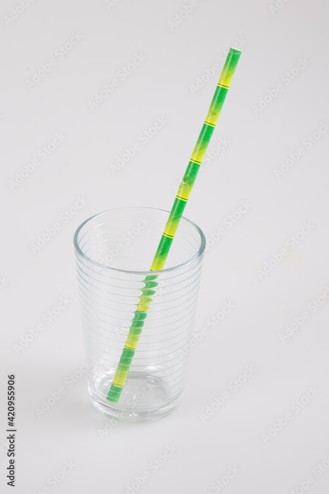 glass transparent empty with green straw in recyclable cardboard on a grey table background glass transparent empty with green straw in recyclable cardboard on a grey table background