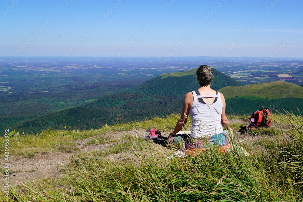 sporty woman takes a break in front of the landscape natural panorama of old mountain Puy de Dome volcano in Auvergne france