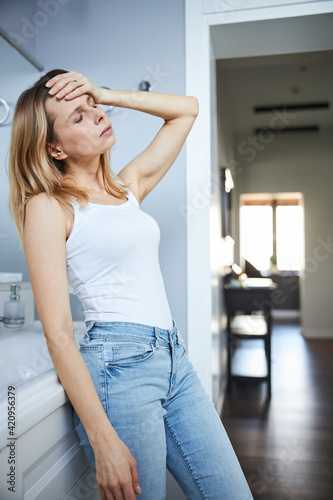Unhappy woman suffering from headache at home