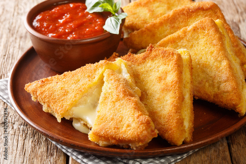 Mozzarella in carrozza is made of sliced bread enclosing the precious creaminess of the mozzarella closeup in the plate on the table. horizontal photo
