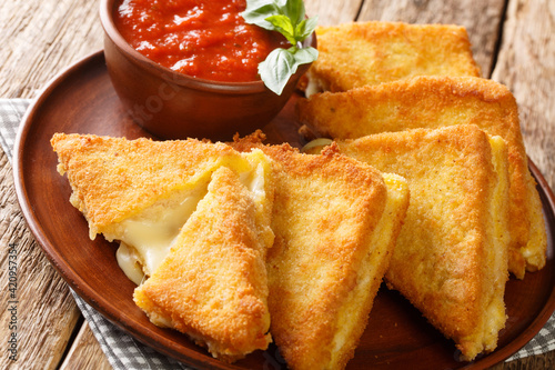 Mozzarella in carrozza is an Italian cheese sandwich made by breading and frying mozzarella-stuffed bread closeup in the plate on the table. horizontal photo