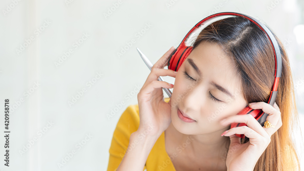 Beautiful Asian woman wearing a yellow shirt and headphones using a laptop in a cafe, write a note Charming female student in language learning, watch online webinar, audio listening course, education Beautiful Asian woman wearing a yellow shirt and headphones using a laptop in a cafe, write a note Charming female student in language learning, watch online webinar, audio listening course, education