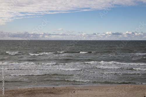 Beautiful view of wavy sea on a sunny day with dramatic clouds. Vacation and holidays background, global warming and climate change concept