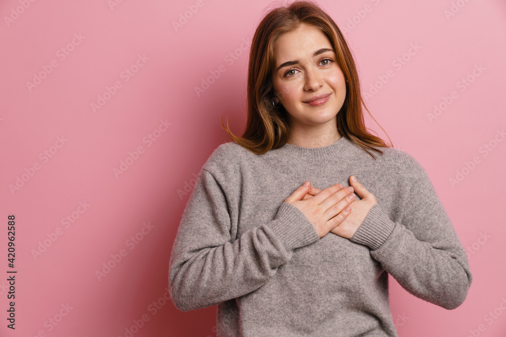 Ginger young happy woman smiling while holding hands on her chest Ginger young happy woman smiling while holding hands on her chest