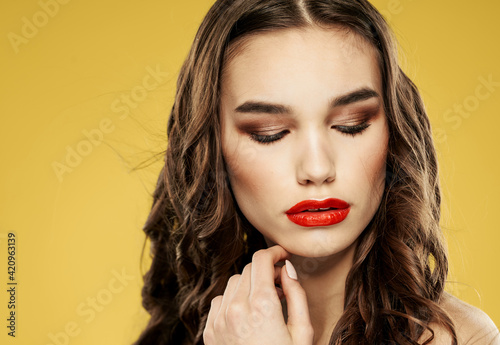 Fototapeta Naklejka Na Ścianę i Meble -  Beautiful brunette with red lips eyeshadow and yellow background