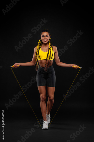 Women with jumping rope on black background. Beautiful young women standing with a jumping rope photo