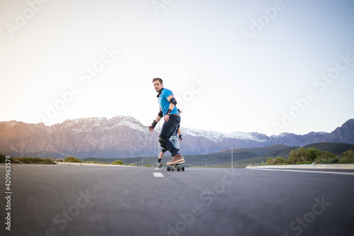 Skateboarder skateboarding on an open road doing freestyle tricks © Dewald