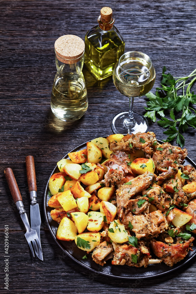 braised Rabbit with potatoes on a black plate