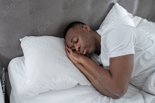 A young man in white sleeping and looking peaceful