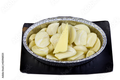 Peeled garlic, sliced ​​in a cup foil on a tile tray.