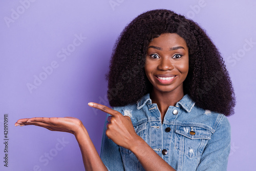 Photo of happy cheerful good mood smiling african girl point finger demonstrate product isolated on violet color background
