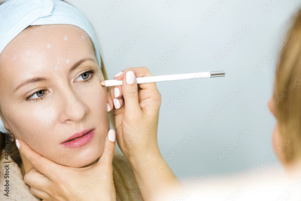 Woman at a beauticians appointment. A specialist examines it and makes markings with a special pencil. Non-surgical face lifting. SMAS lifting ultrasonic. Facelift