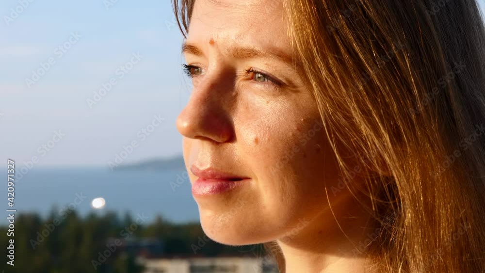 Close Up of Beautiful Woman Portrait at Sunset Enjoying Peaceful Sunset with Wind Blowing Hair with Sea on Background. Outdoor Relax Sunlight, Slow Motion Close Up of Beautiful Woman Portrait at Sunset Enjoying Peaceful Sunset with Wind Blowing Hair with Sea on Background. Outdoor Relax Sunlight, Slow Motion