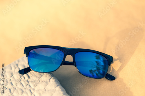 Classic sunglasses model with blue lenses and black frame shoot in a summer day closeup . Selective focus. High quality photo