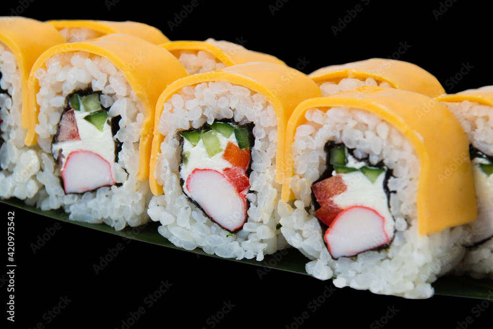 Sushi rolls with crab stick, philadelphia cheese, cucumber and red bell pepper, close up on black background Sushi rolls with crab stick, philadelphia cheese, cucumber and red bell pepper, close up on black background
