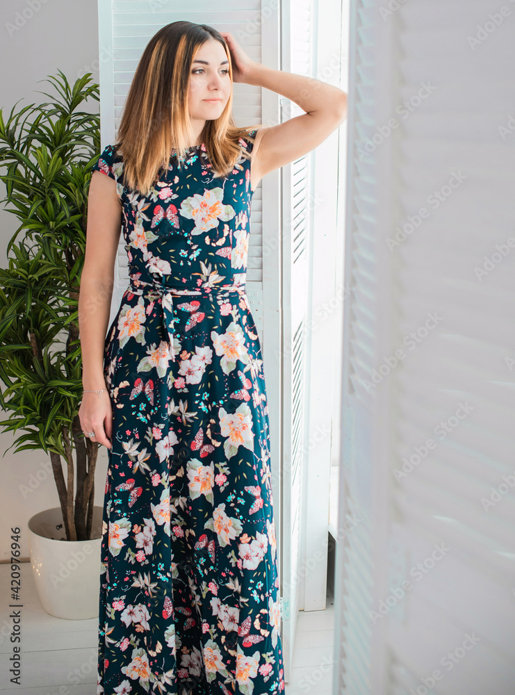 Woman Arabic appearance in flower cotton long dress posing indoors, fashionable concept Woman Arabic appearance in flower cotton long dress posing indoors, fashionable concept