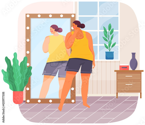 Woman in sportswear looking at reflection in mirror. Unhappy plump girl standing in front of mirror