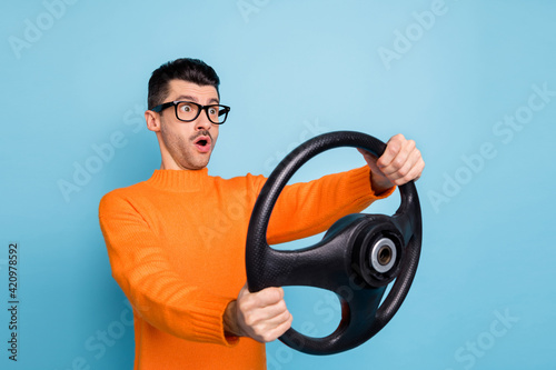 Photo of young man amazes shocked surprised drive auto hold steering-wheel look empty space isolated over blue color background