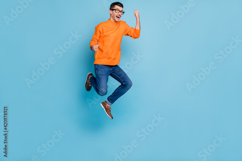 Full body profile portrait of astonished man open mouth fists up look empty space isolated on blue color background