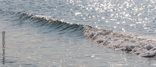 Petit rouleau de vague sur la mer en contre-jour et scintillement de l'eau, format bannière photo