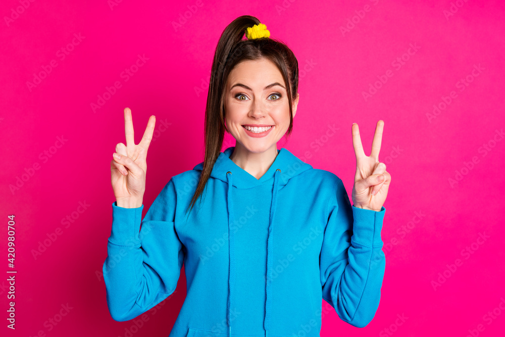 Portrait of funky pretty young person beaming smile finger show v-sign isolated on pink color background