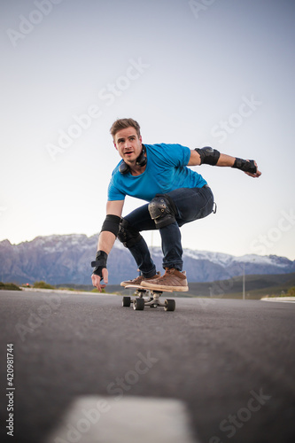 Close up image of a skateboarder skating his skateboard down the road.