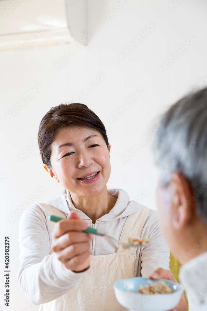 食事介助する日本人のミドル女性、在宅介助、ヘルパー