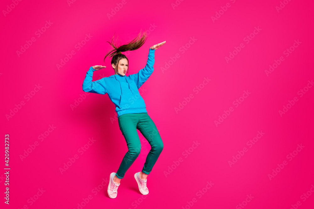 Full length photo of pretty funky young woman dressed blue hoodie dancing standing tiptoes isolated vibrant pink color background