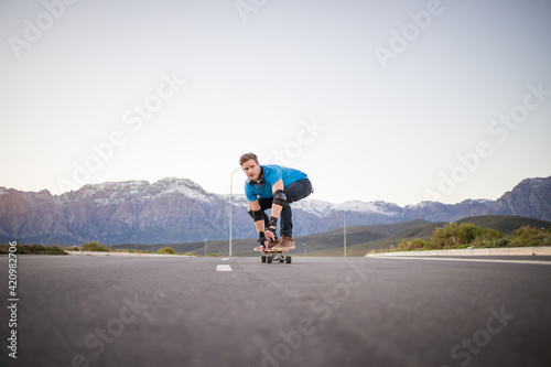 Skateboarder skateboarding on an open road doing freestyle tricks © Dewald