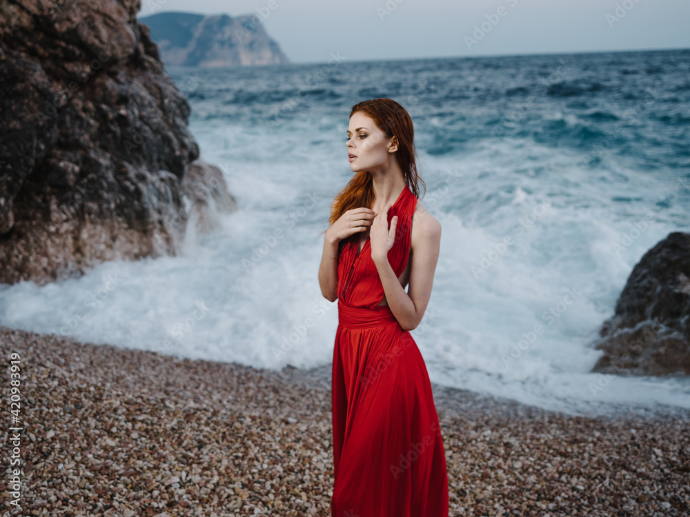 Woman in red dress sea waves beach landscape Woman in red dress sea waves beach landscape