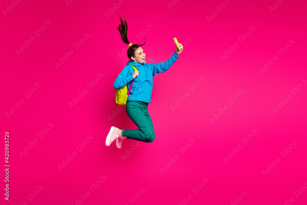 Full length photo of funny sweet young woman dressed blue hoodie rucksack taking selfie modern device isolated pink color background