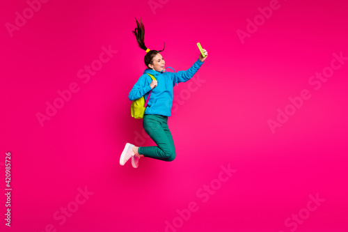 Full length photo of funny sweet young woman dressed blue hoodie rucksack taking selfie modern device isolated pink color background