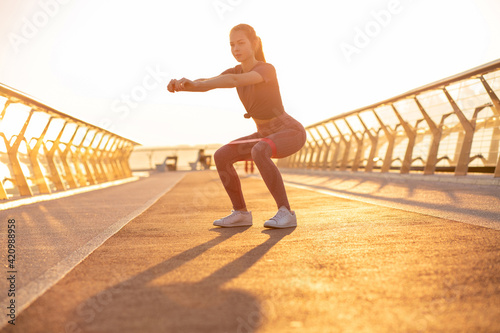 Athletic red head woman doing squats with an expander