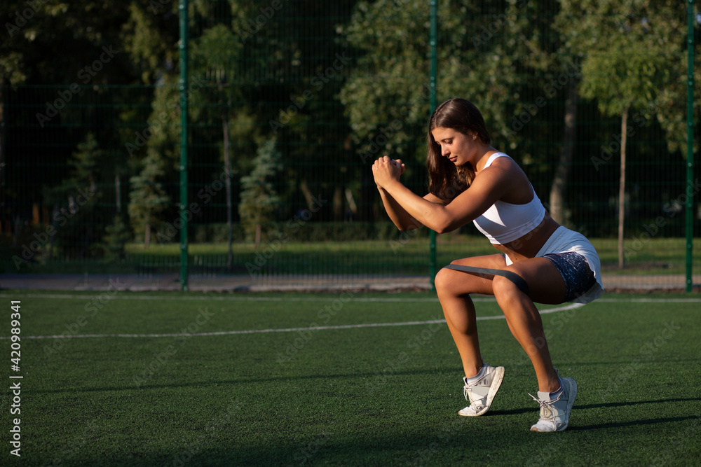 Strong sportswoman having training with rubber band