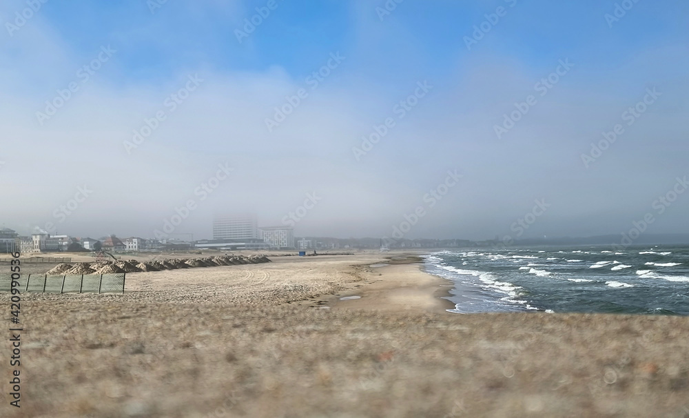 Blick über die Molenmauer auf den Strand in Warnemünde im Nebel