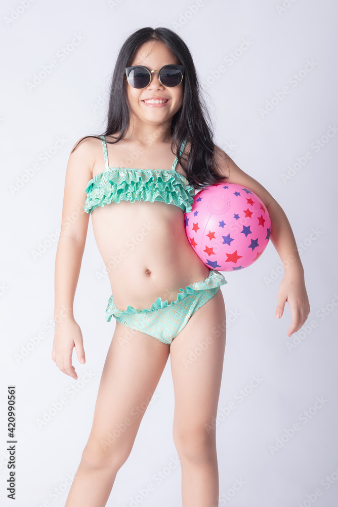 child bikini holding a beach ball. little stylish lady girl in swimsuit,  relaxing isolated white background. lovely photo for advertising,copy space  for text. beach vacation concept. Stock Photo