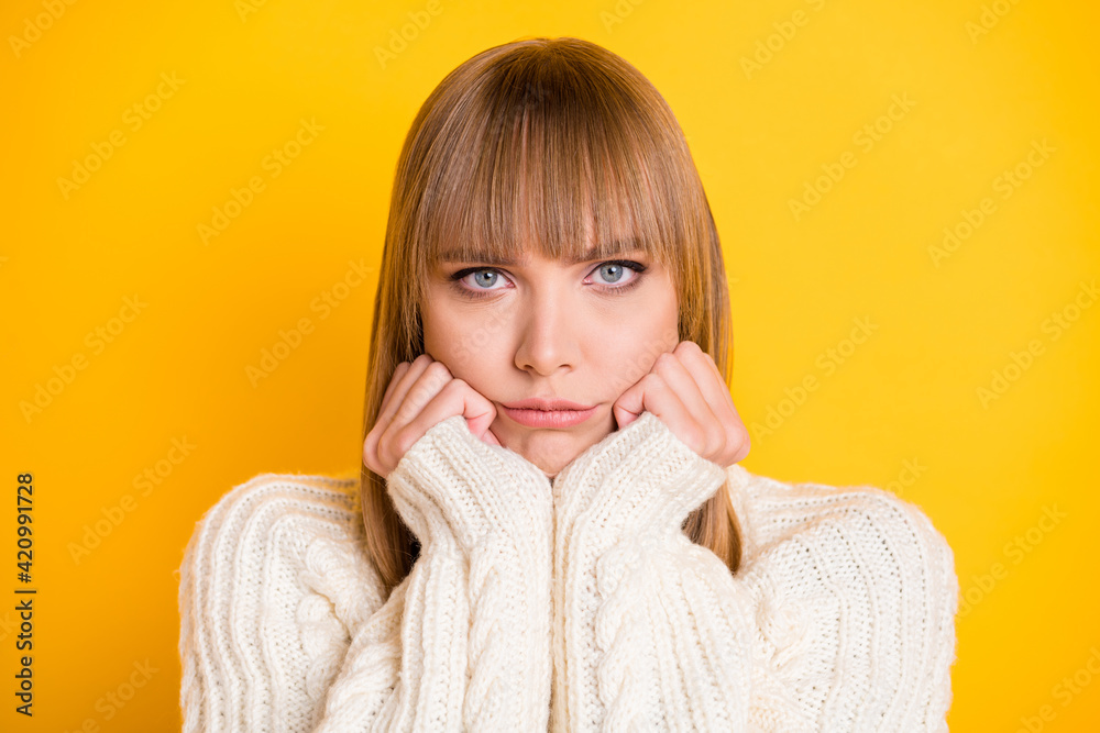 Photo of displeased young girl arms on cheeks pouted lips wear warm sweater isolated on yellow color background Photo of displeased young girl arms on cheeks pouted lips wear warm sweater isolated on yellow color background